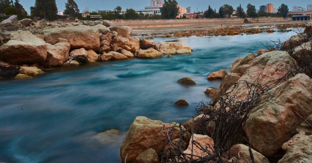 Captivating long exposure photograph of the Seyhan River in Adana, Türkiye, featuring smooth water and rocky shores.