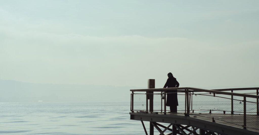 A lone figure stands on a pier, gazing over the calm sea in İzmir, Türkiye.