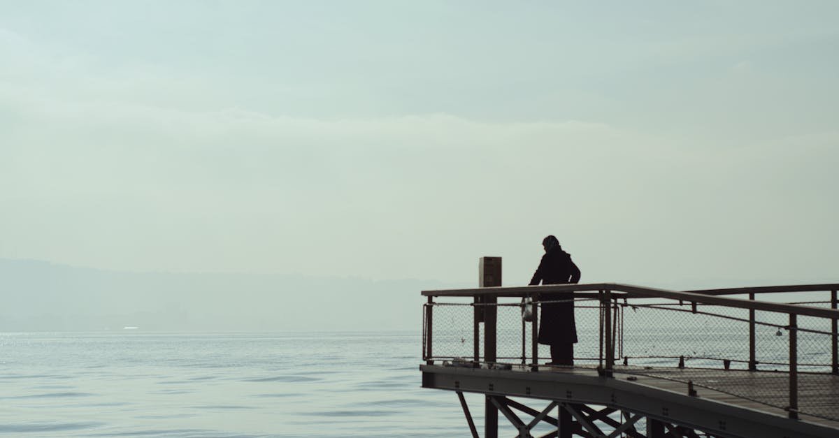 A lone figure stands on a pier, gazing over the calm sea in İzmir, Türkiye.