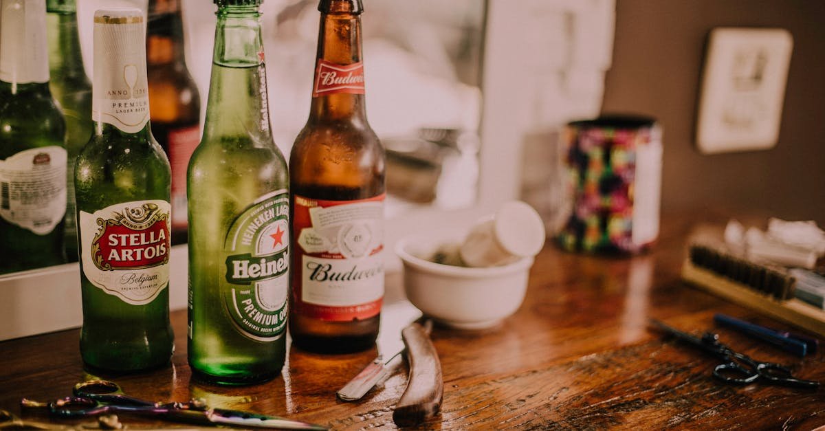 Beer bottles and barber tools on a wooden barbershop counter with a blurred mirror reflection.