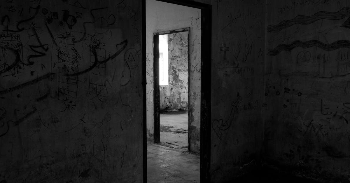 Dark, abandoned building interior with eerie shadows and graffiti-covered walls.