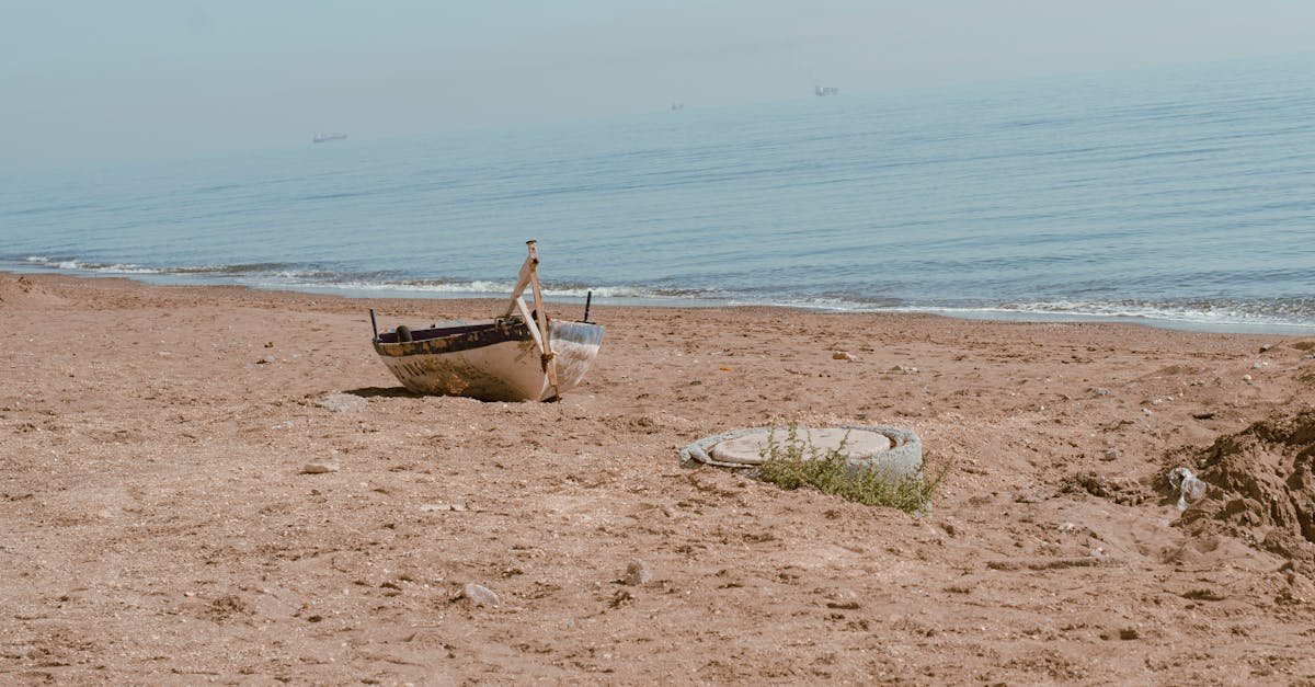 A solitary abandoned boat on the sandy shores of Mersin, Turkey, under clear skies.