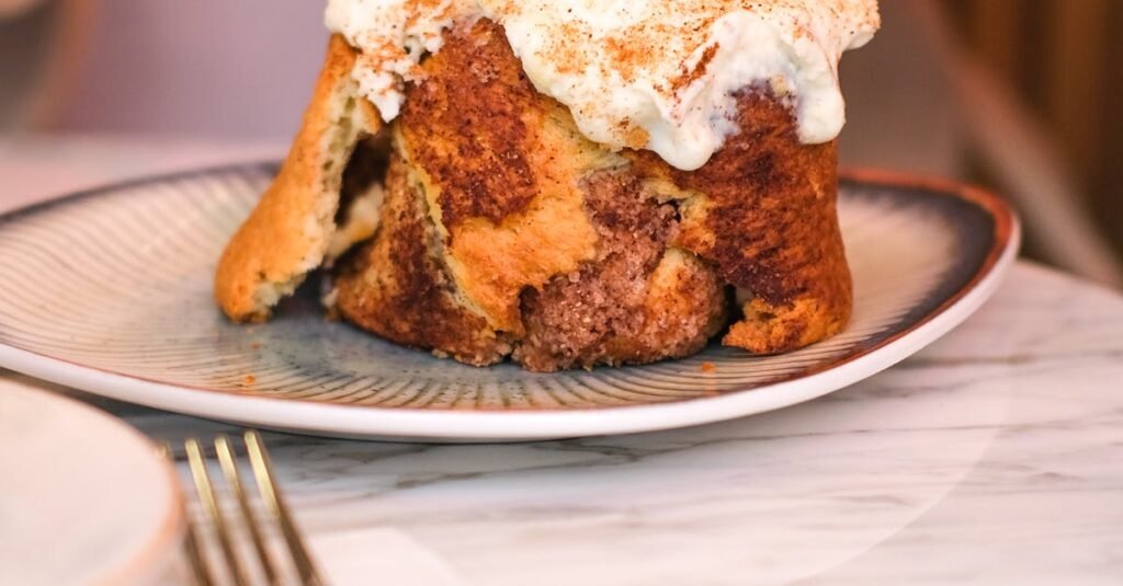 A tasty cinnamon bun being sliced with a fork and knife at an Istanbul café.