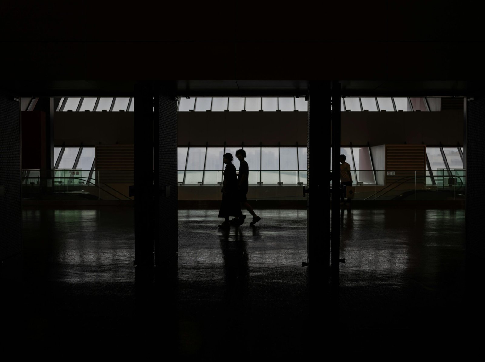 Silhouette of people walking through a modern hallway with large windows in Shanghai, China.