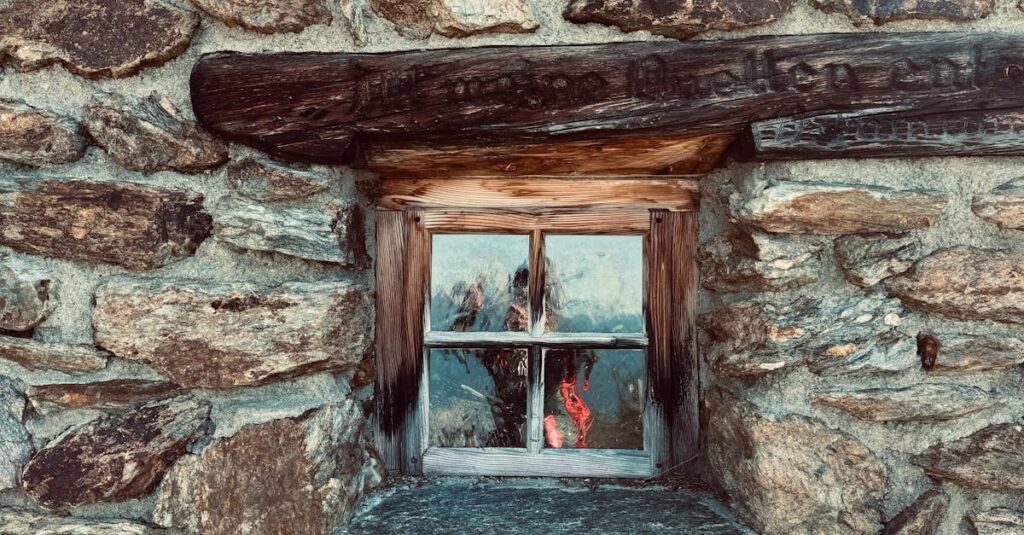 A vintage wooden-framed window on a rustic stone wall, showcasing architectural charm.