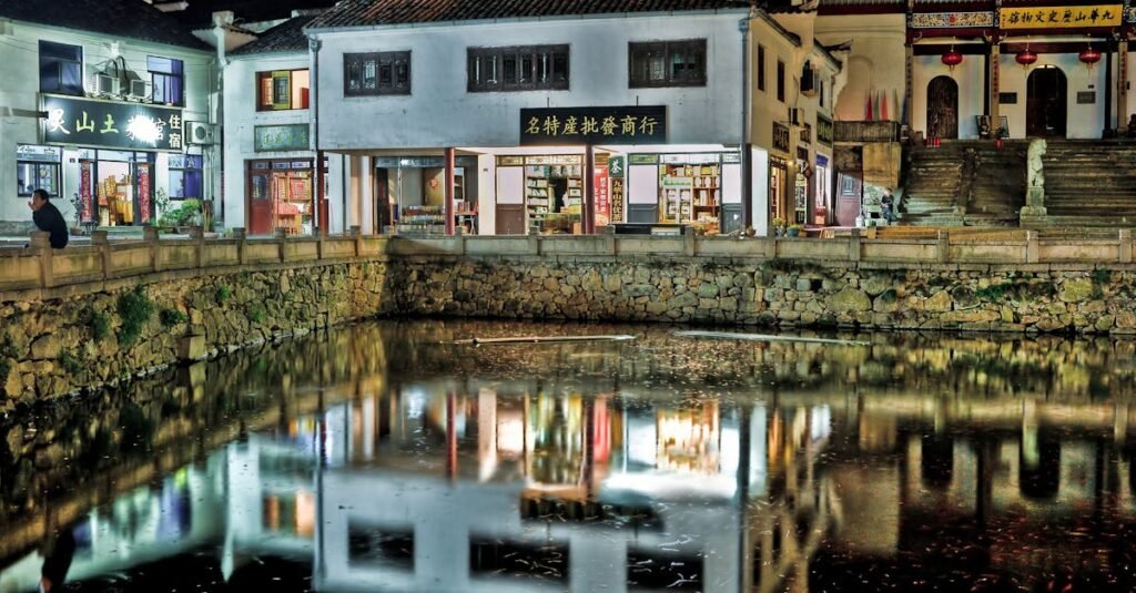 Vibrant city night scene with building lights reflecting in a calm pond.