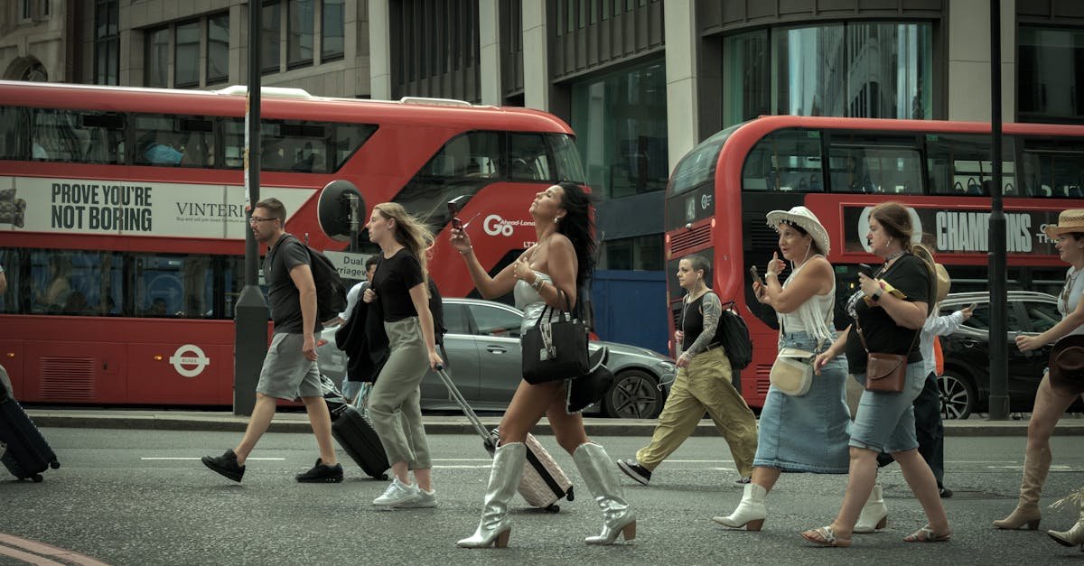 Crowd crossing a London street with iconic red buses in motion, capturing urban life.