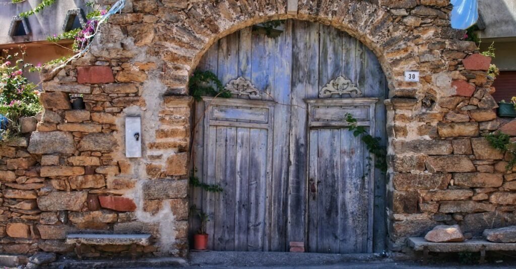 Historic stone archway with wooden doors in sunny Sardinia, Italy.