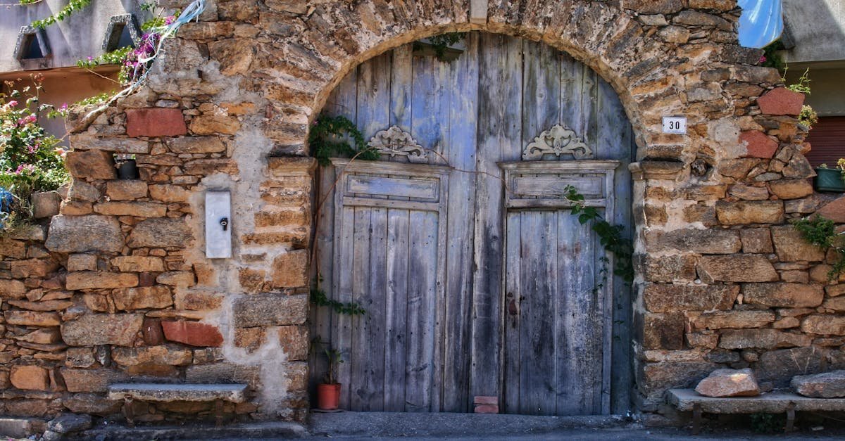 Historic stone archway with wooden doors in sunny Sardinia, Italy.