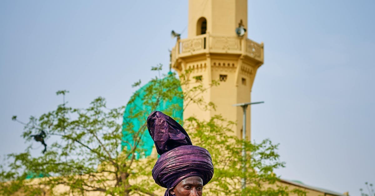 Vibrant traditional horse riders in colorful attire near a mosque tower in Nigeria.