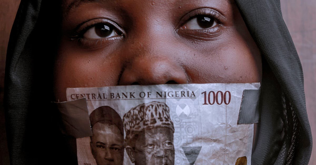 Portrait of a woman with Nigerian currency covering her mouth, illustrating silence and economic expression.