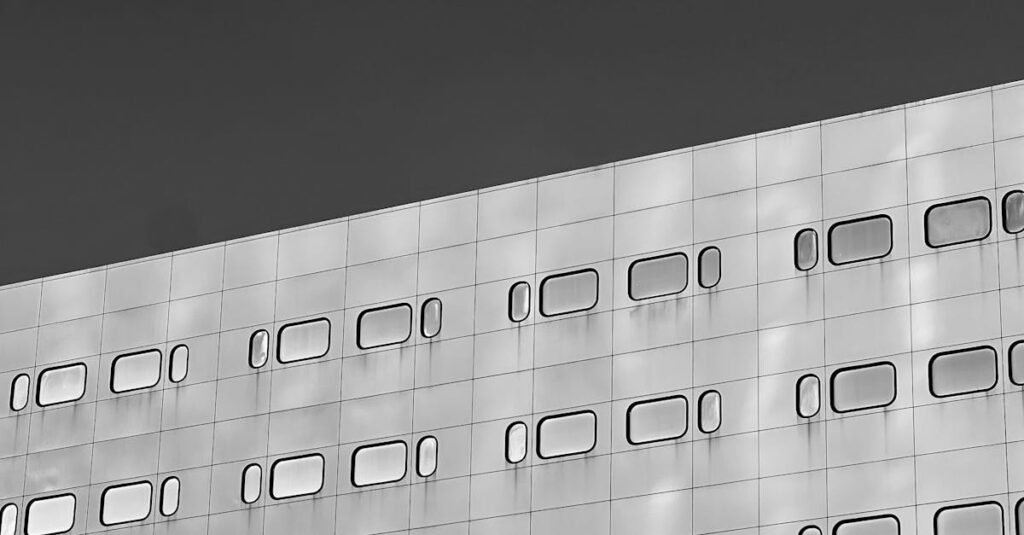 Black and white photo of a minimalist building facade with geometric windows in grid pattern.
