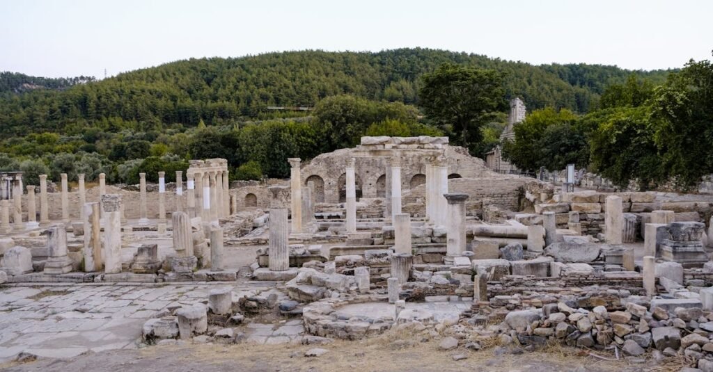 Explore the historical ruins in Muğla, Türkiye, surrounded by lush greenery and ancient marble columns.