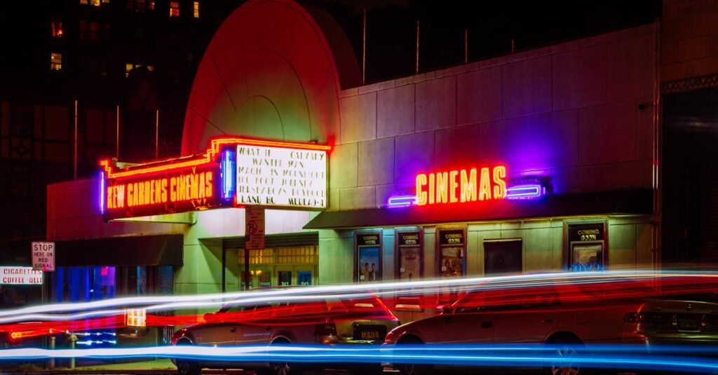 Vibrant night view of New Gardens Cinemas in Queens, New York with colorful neon lights and light streaks.