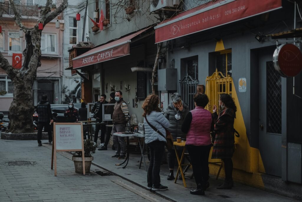 People in winter clothing gather outside cafes in Istanbul's Kuzguncuk district, highlighting urban culture.