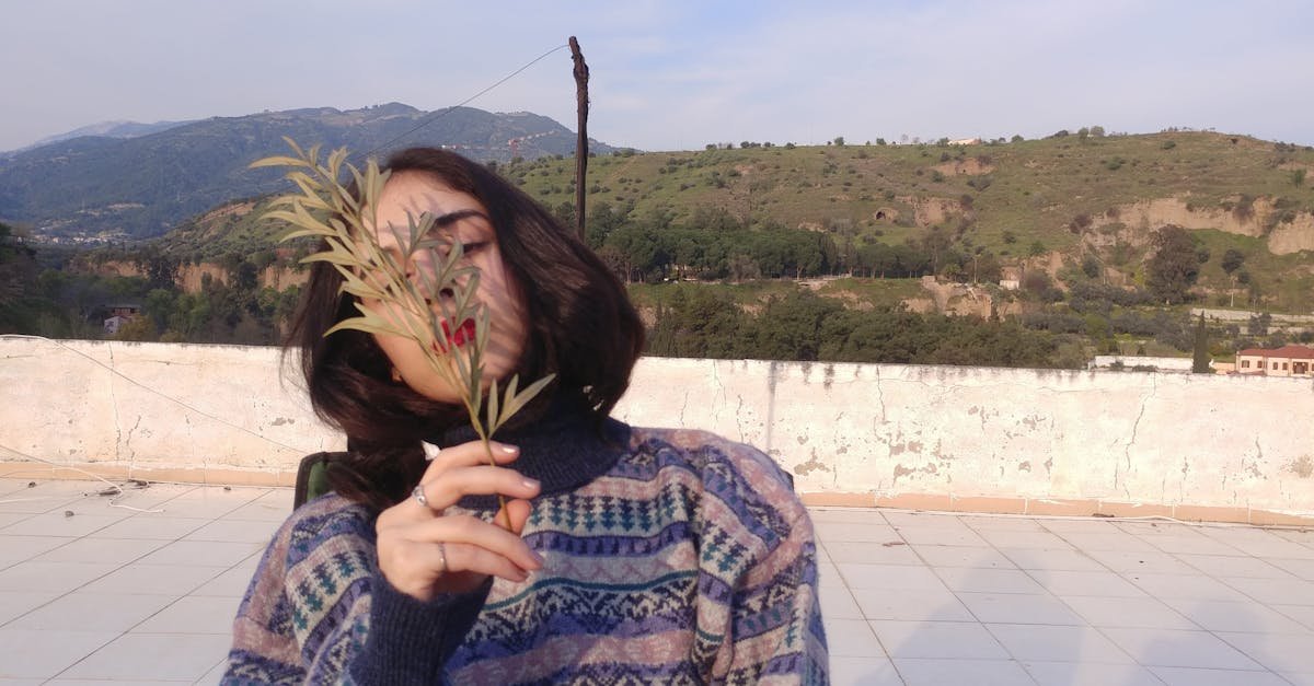 Woman sitting outdoors covering face with leaves, in Aydın, Turkey.