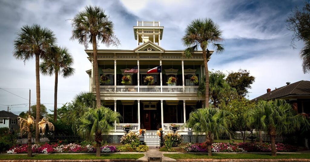 Stunning view of a historic mansion with lush gardens and palm trees in Galveston, Texas.