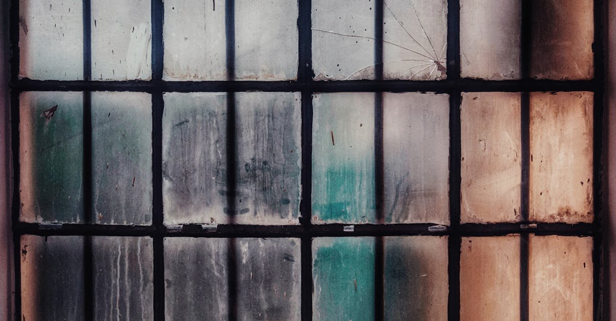 A weathered and dirty glass window with a rusty frame, featuring textured panes and a vintage look.