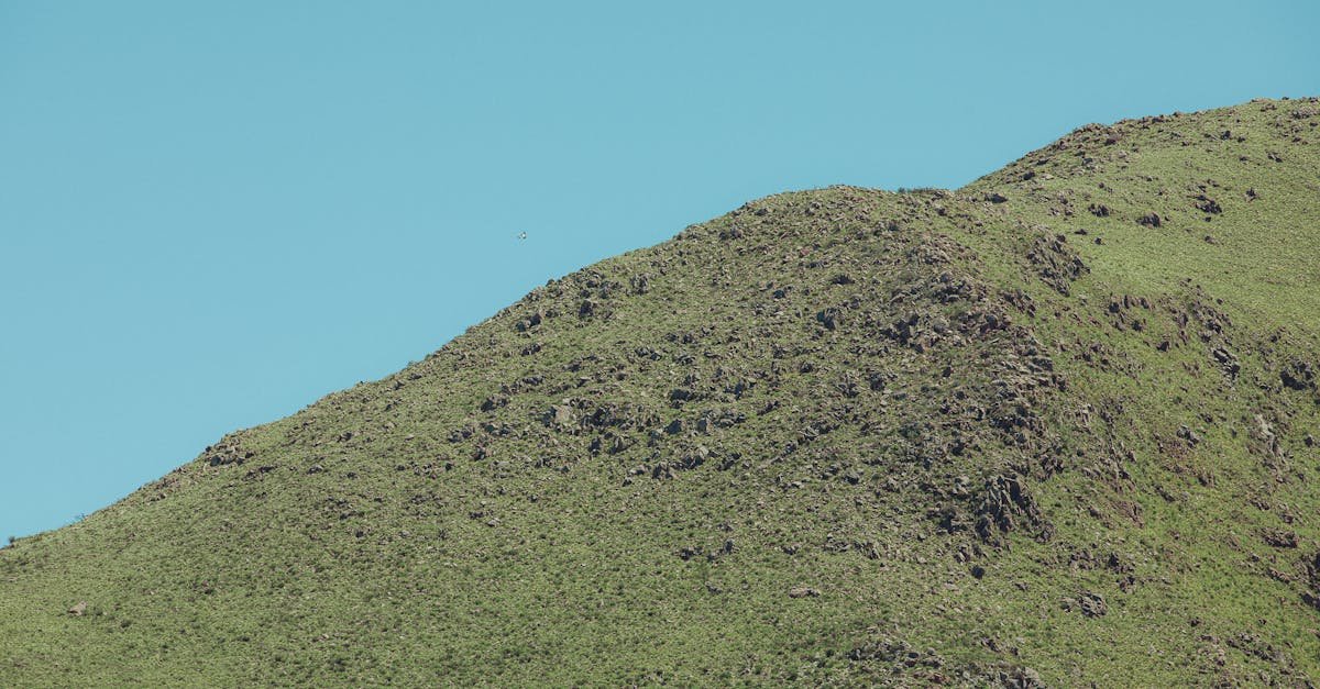 Beautiful green hills with minimal rocky outcrop under a clear blue sky, captured in Córdoba, Argentina.