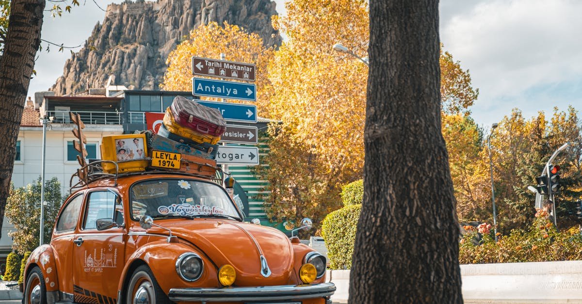 Classic orange Volkswagen Beetle with luggage, parked in Afyonkarahisar, Türkiye under autumn leaves.