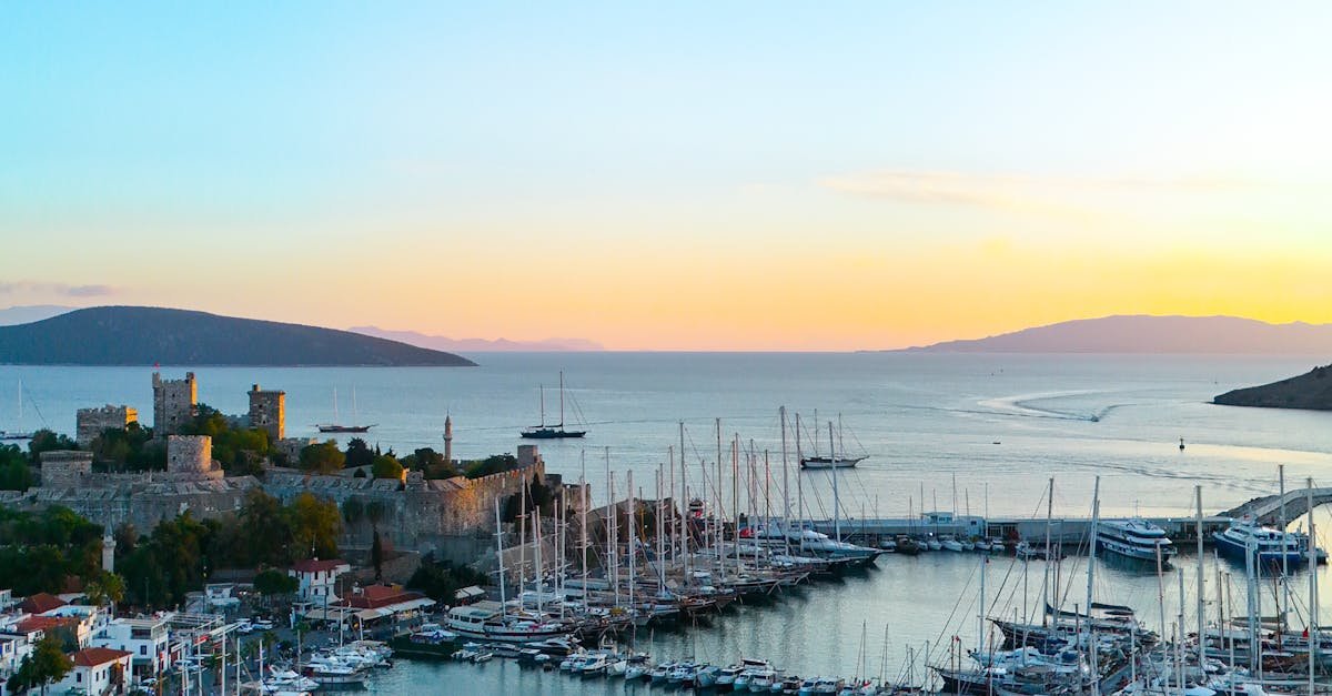 Scenic sunset over Bodrum Marina with yachts and castle on Turkey's coast.