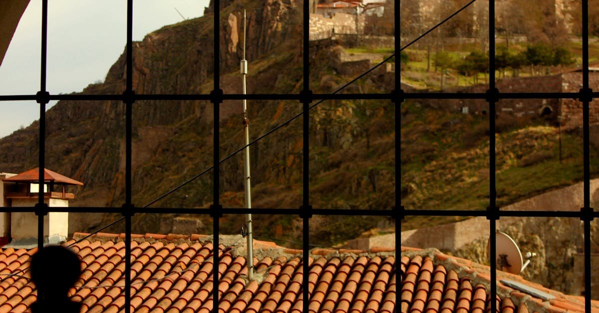 A scenic view through an arched window framing a historic fortress on a hill.