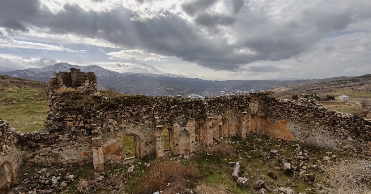 Ancient ruins in Palu, Elazığ, Türkiye, against a dramatic mountain backdrop under cloudy skies.
