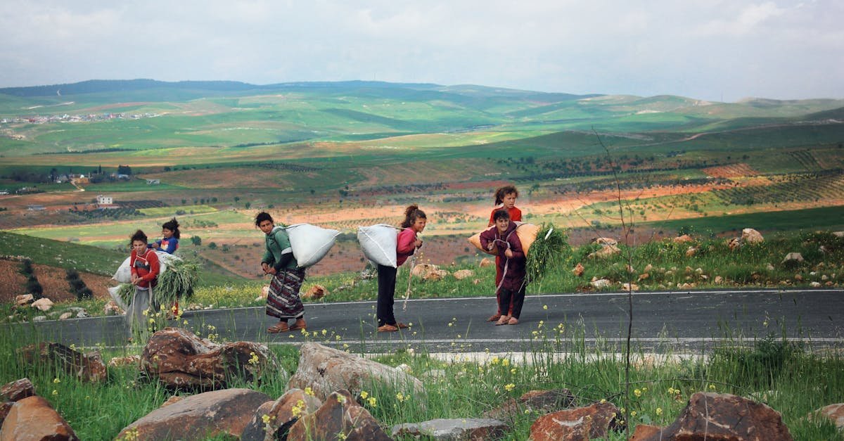 Children walking along a rural road with sacks in Şanlıurfa, Türkiye, amid lush green landscapes.