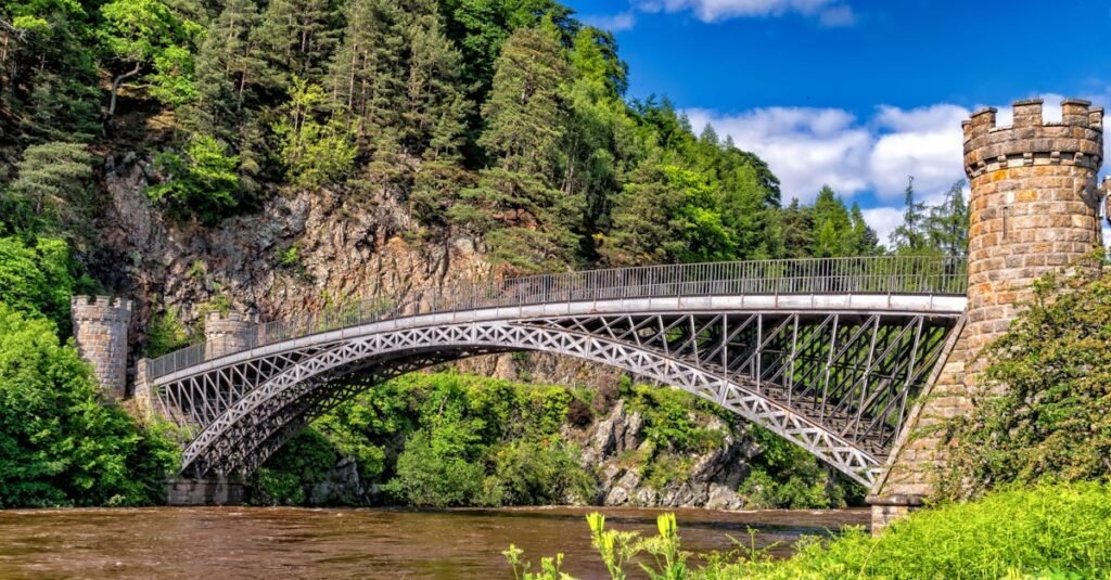 Scenic view of a historic bridge amidst lush greenery and rocky cliffs.