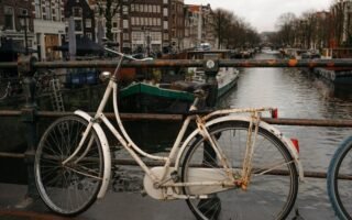 A vintage bicycle parked by an Amsterdam canal, capturing iconic Dutch scenery.