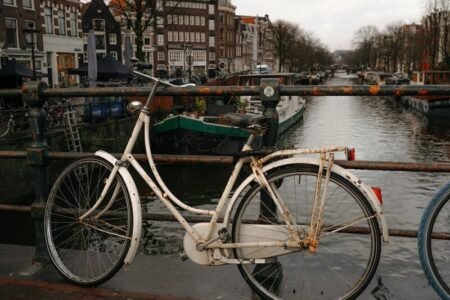 A vintage bicycle parked by an Amsterdam canal, capturing iconic Dutch scenery.