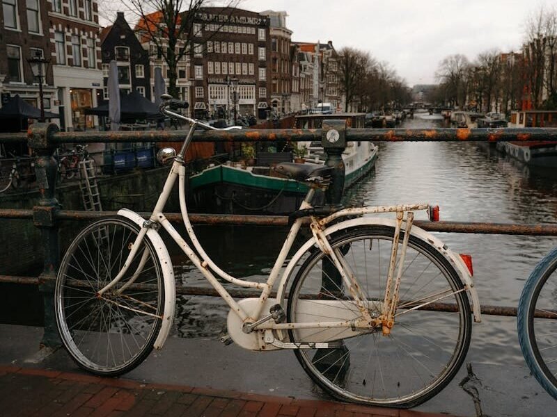A vintage bicycle parked by an Amsterdam canal, capturing iconic Dutch scenery.