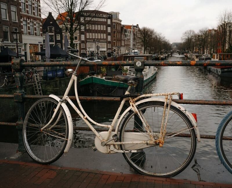 A vintage bicycle parked by an Amsterdam canal, capturing iconic Dutch scenery.