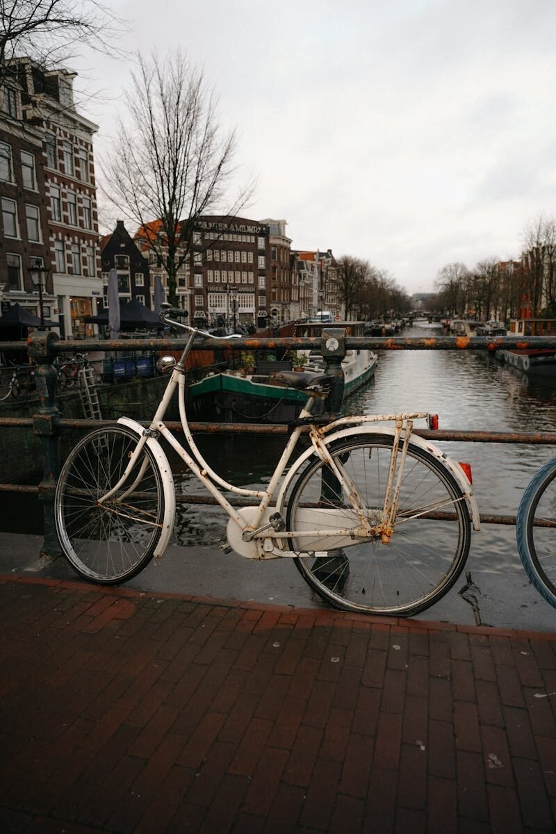 A vintage bicycle parked by an Amsterdam canal, capturing iconic Dutch scenery.