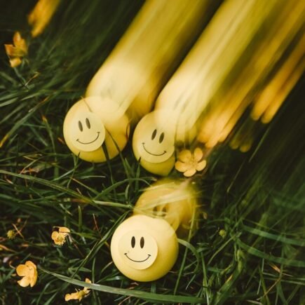 Yellow smiley balls rolling on green grass
