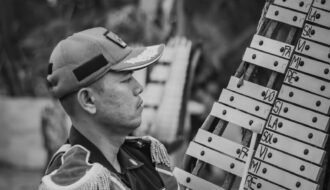 Black and white image of a musician playing a xylophone outdoors.