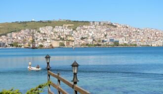 Explore the beautiful waterfront and cityscape of Sinop, Türkiye, with serene water and lush hills.