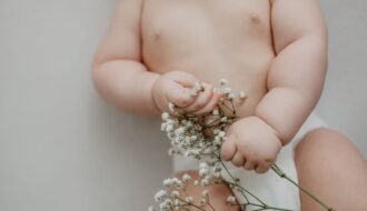 A cute baby gently holding delicate white flowers, symbolizing innocence and new life.