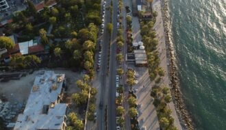 Aerial shot of Kuşadası's seafront and lush cityscape, featuring palm-lined streets.