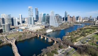 Aerial view of Austin, Texas skyline with landmarks including river and footbridge.