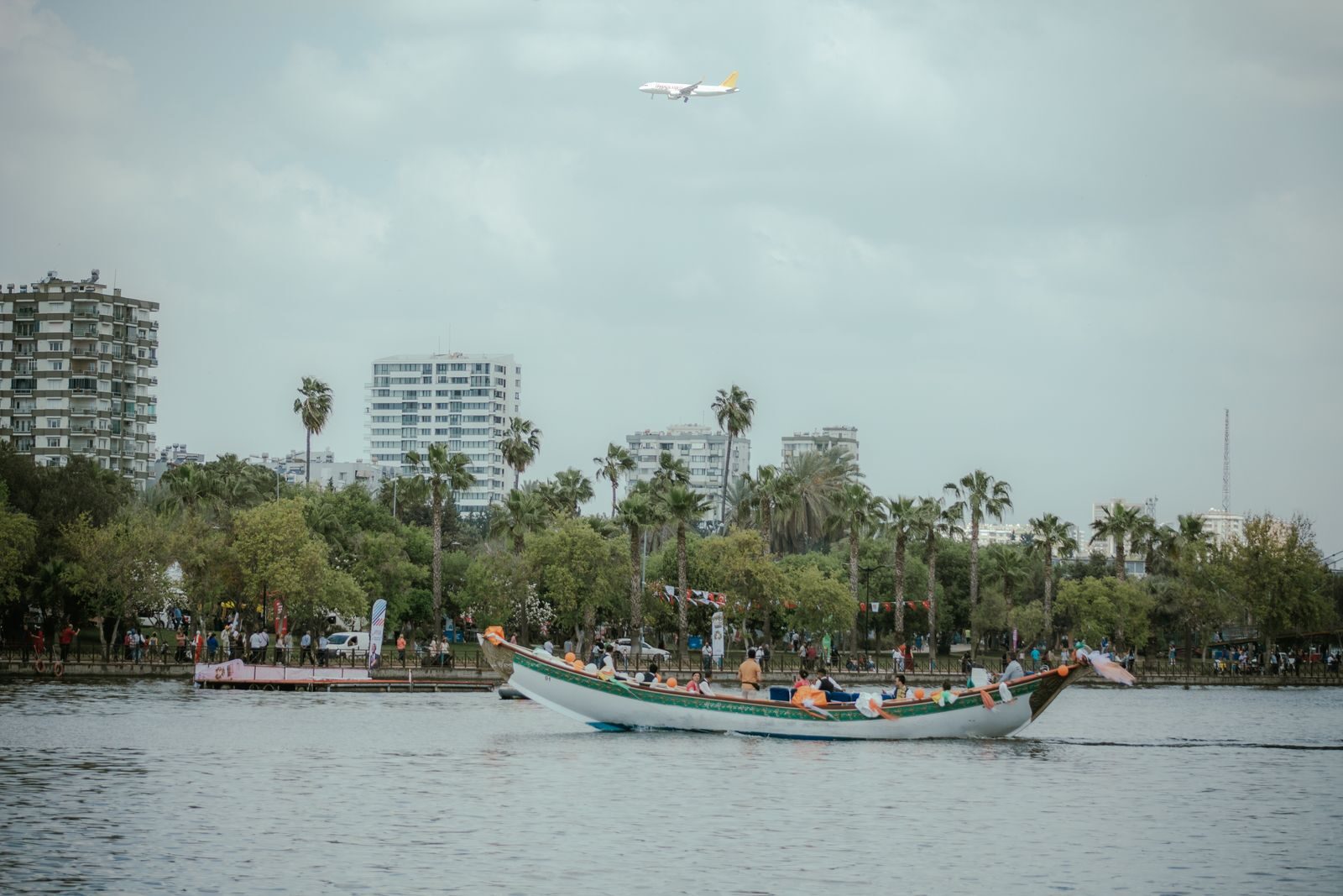 A picturesque view of a boat on the river, with buildings and an airplane in Adana, Türkiye.