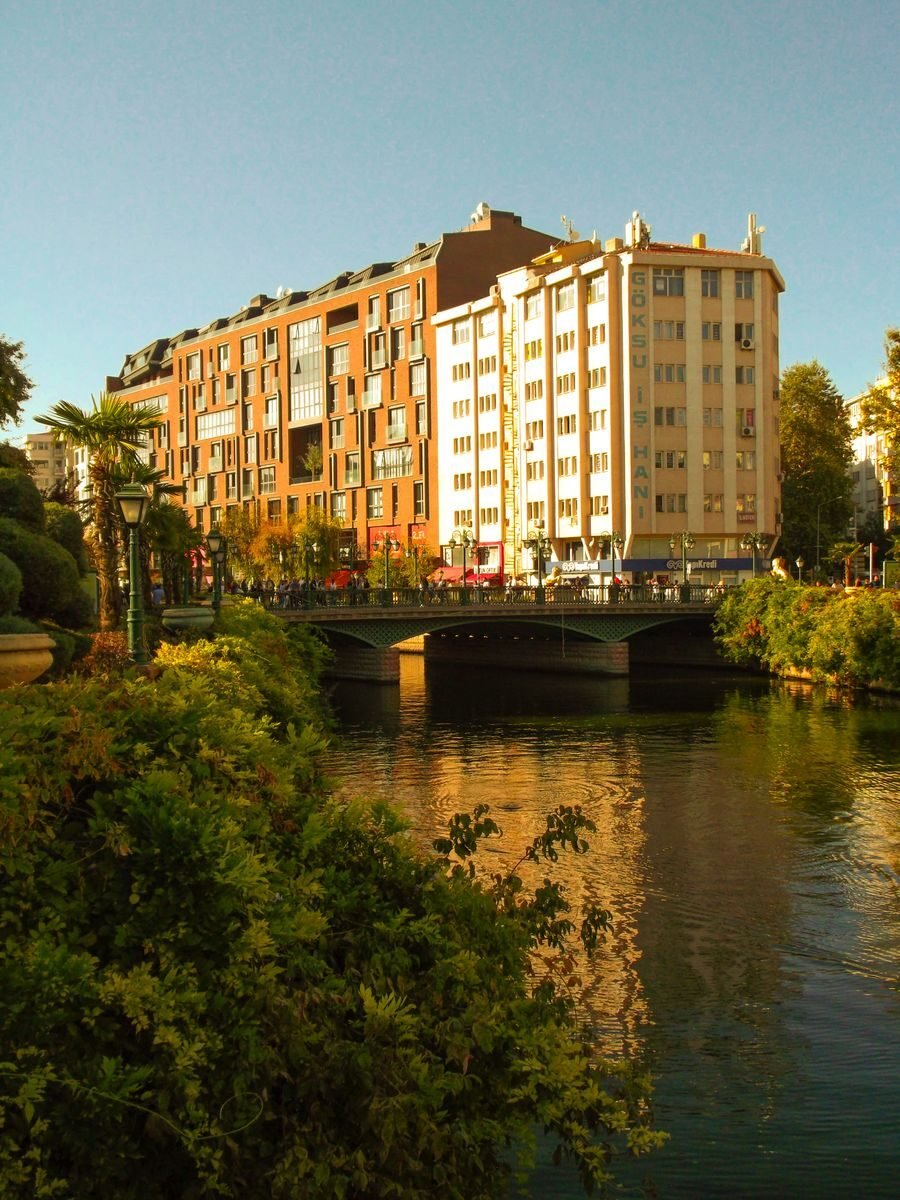 Charming urban riverside view in Eskişehir with lush greenery and modern architecture.