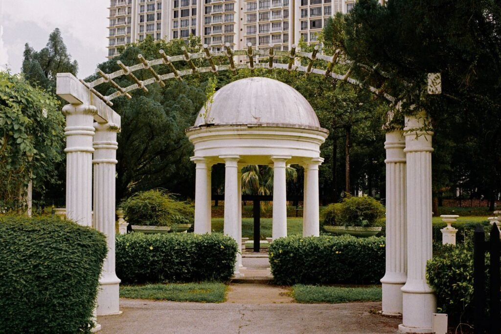 Beautiful white gazebo with pillars in a lush Malaysian garden. Perfect for serene moments.
