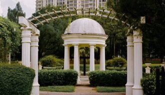 Beautiful white gazebo with pillars in a lush Malaysian garden. Perfect for serene moments.