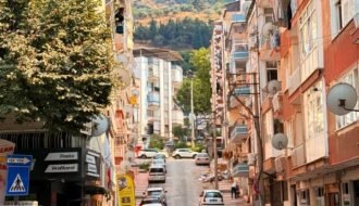 Charming urban street scene in Manisa, Türkiye with vibrant buildings and a hilly backdrop.