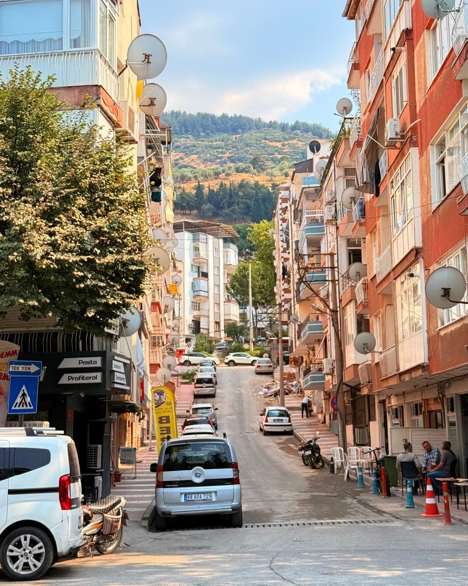 Charming urban street scene in Manisa, Türkiye with vibrant buildings and a hilly backdrop.