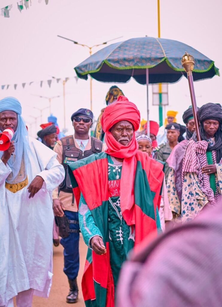 Vibrant cultural parade with participants in traditional attire, holding a ceremonial umbrella.