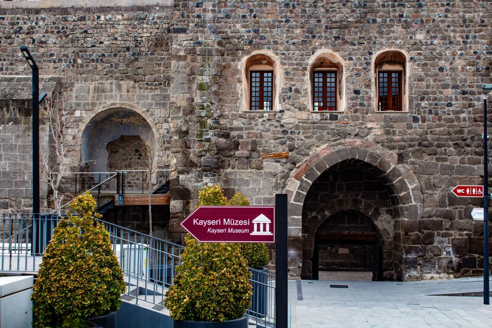 Stone building facade of Kayseri Museum with directional sign, showcasing historic architecture.