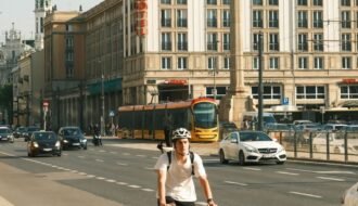 A cyclist rides through bustling Warsaw streets, showcasing urban life on a sunny day.