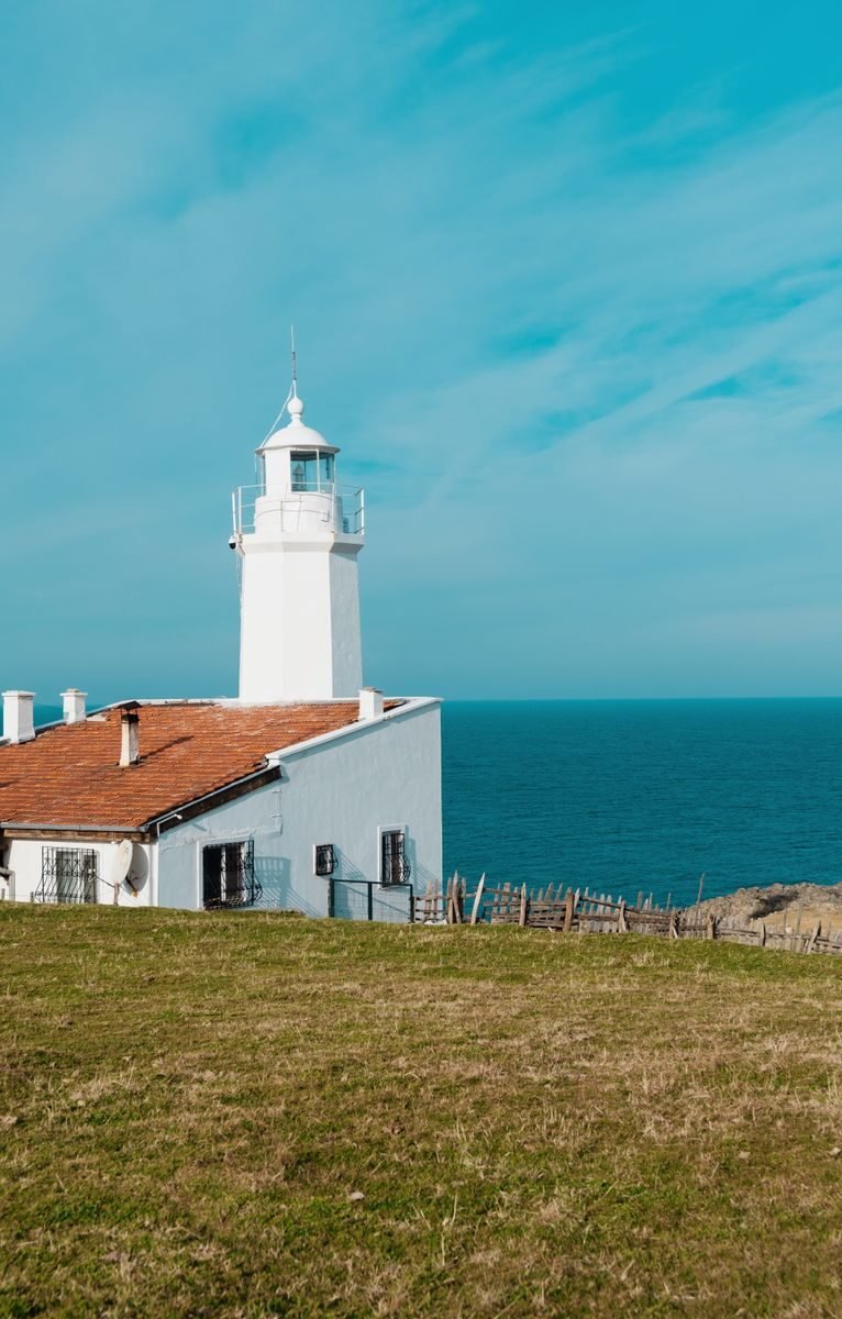 A beautiful seaside lighthouse against a clear blue sky in Sinop, Türkiye, showcasing serene coastal beauty.